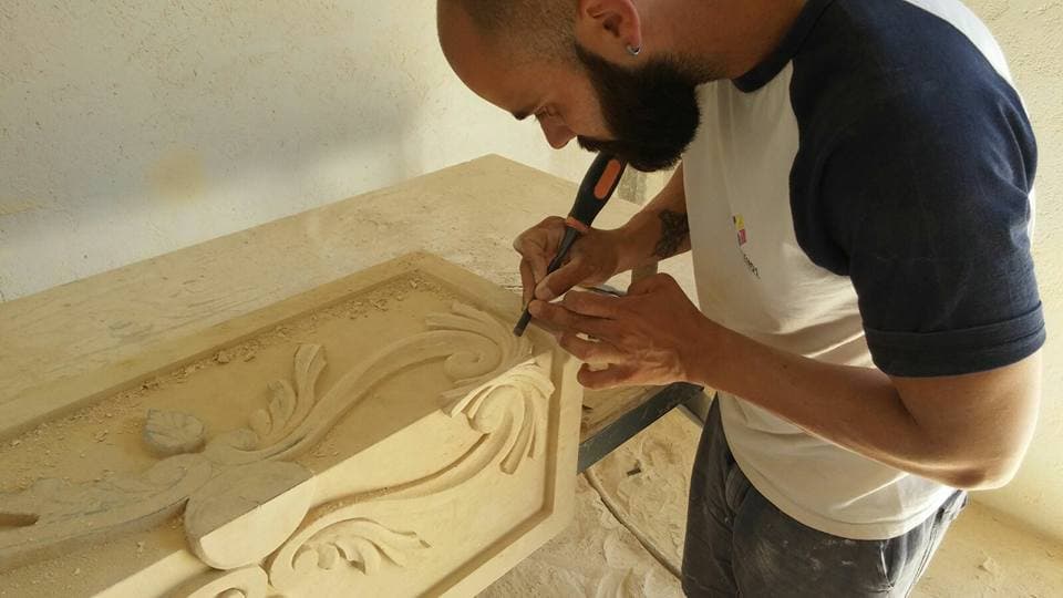 An artisan carving a piece of stone in a workshop.